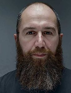 A portrait of Gigi Giannella. He is semi-bald and has a long bushy beard,