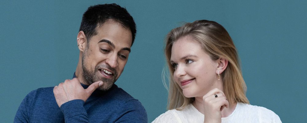 A man and woman stood side by side, smiling and posing cheerfully