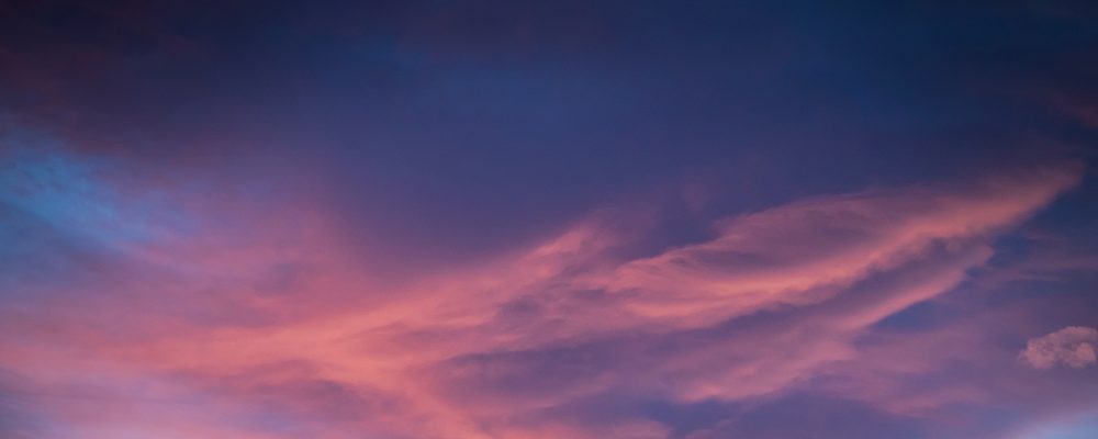 A sky at dusk with a mix of pink and blue clouds.