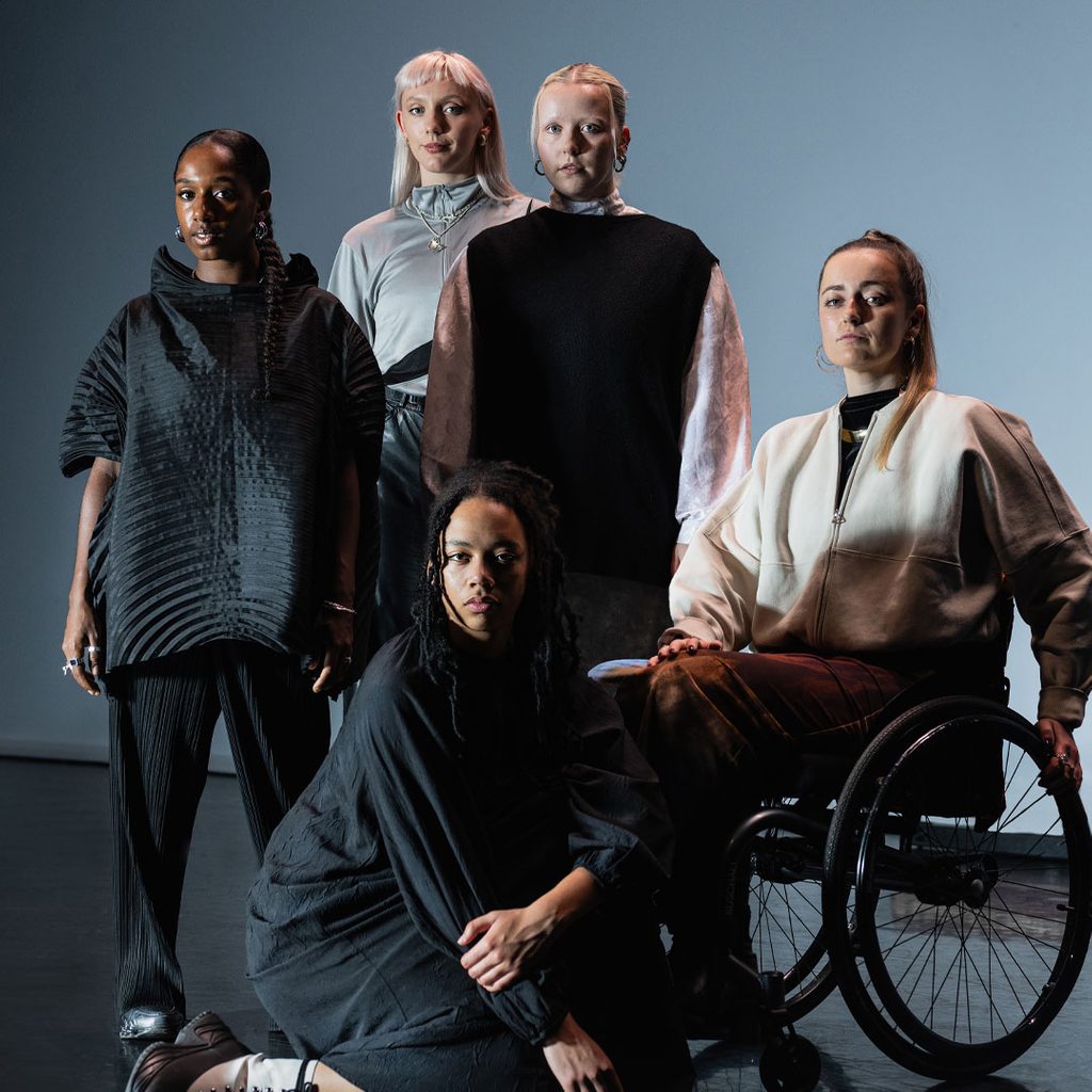 Five young dancers stand for a portrait all together in a studio